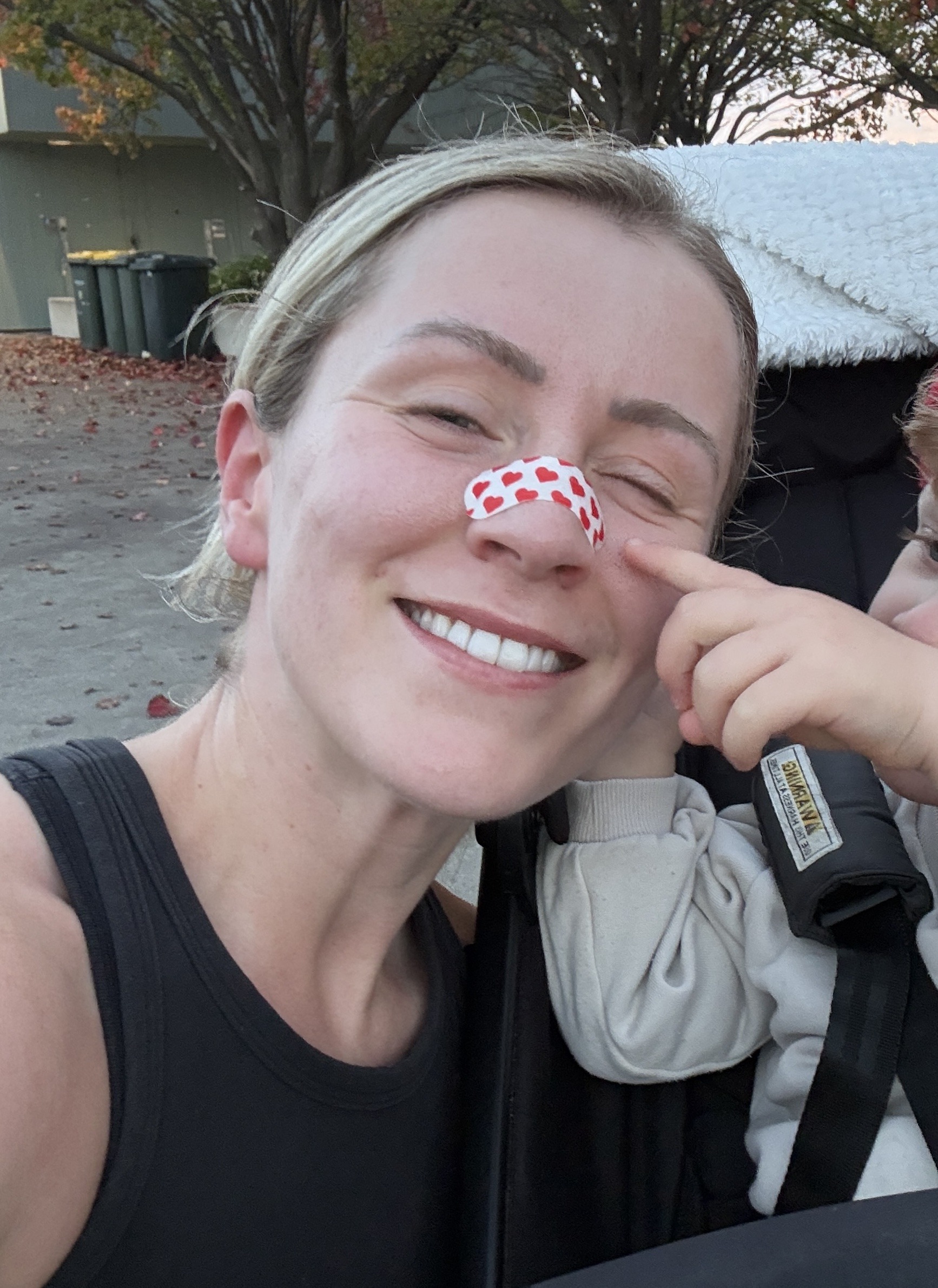 Pretty Ugly customer wearing nose tape, smiling outdoors
